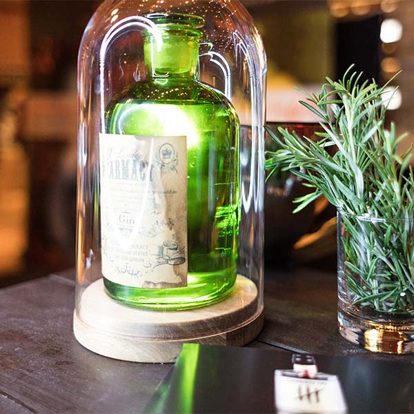 Eine grüne Spirituosenflasche und Rosmarin stehen auf einem Tisch